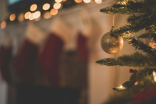 een close up van een gouden blinkende kerstbal aan een kerstboom