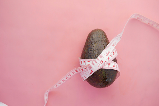 een avocado met een lintmeter rond op een roze achtergrond