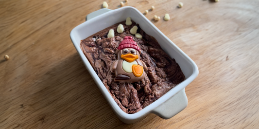 Christmas baked oats met een chocolade pinguïn in een stenen schaal op een houten tafel