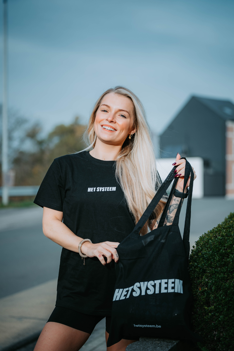 een jong blond model met een totebag van het systeem poserende as ambassadeur