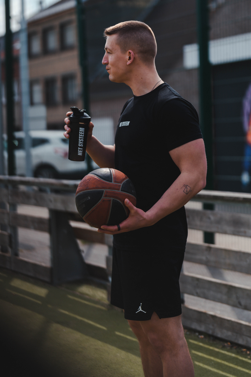 gespierde basketbal speler met een basketbal in de hand en een shakebeker van het systeem
