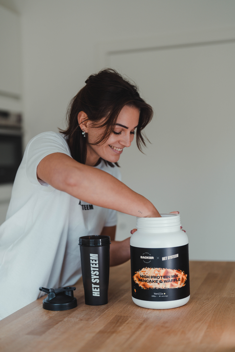 een jonge fitness liefhebber die schep neemt al lachende uit een pot pancake & wafflemix van het systeem