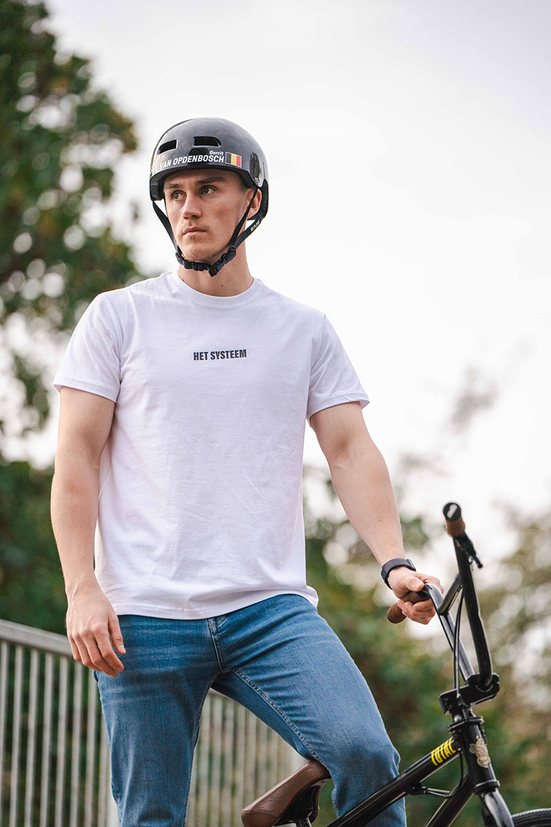een gespierede bmx fietser met een t-shirt van het systeem poserende als ambassadeur